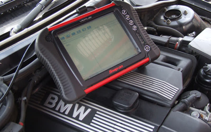 A diagnostic scan tool plugged in and reading fault codes from a car engine